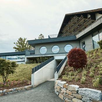 Karnerhof live. Modern hotel building with circular windows and landscaped garden on a hillside